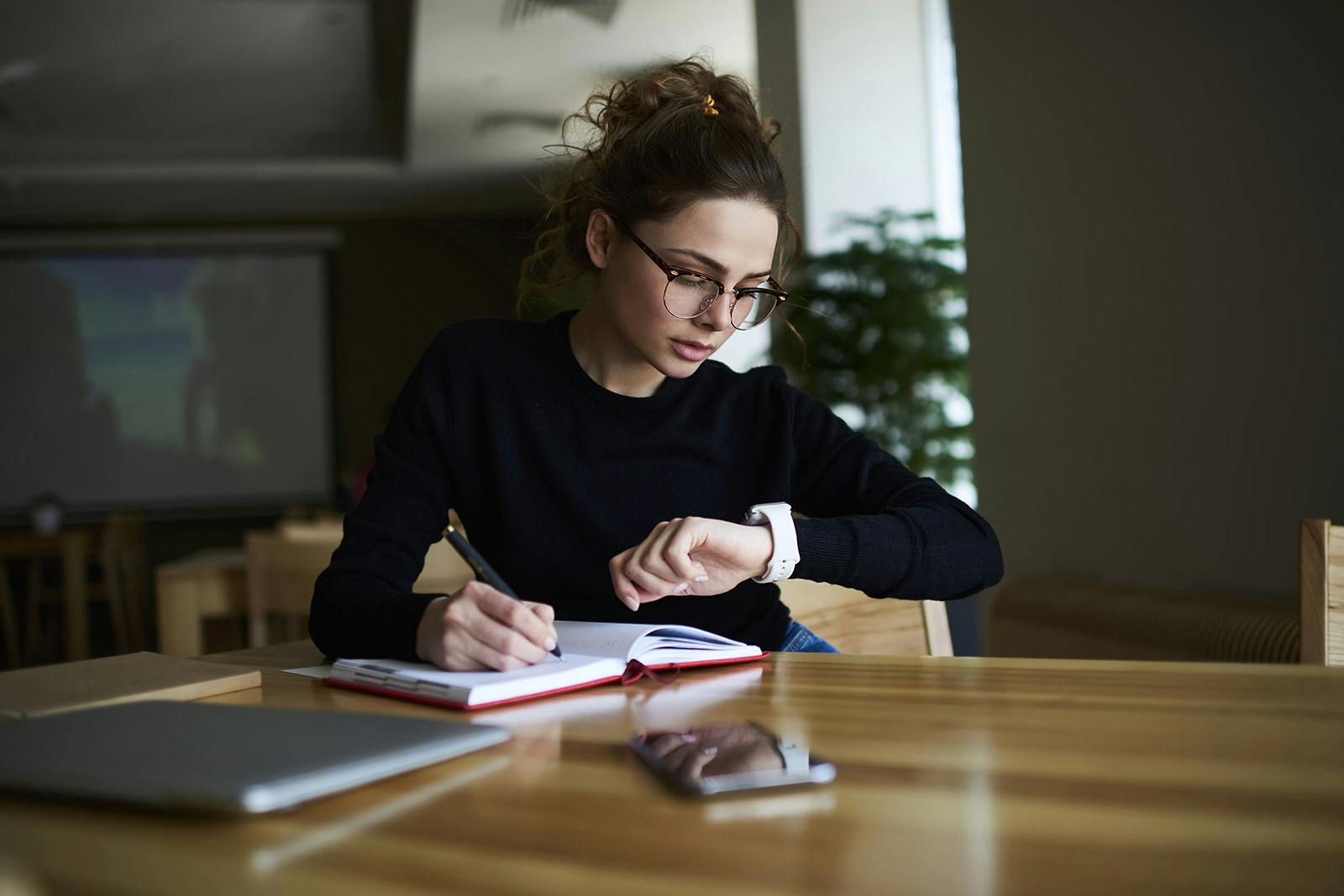 young executive in the conference room checks the time on her watch