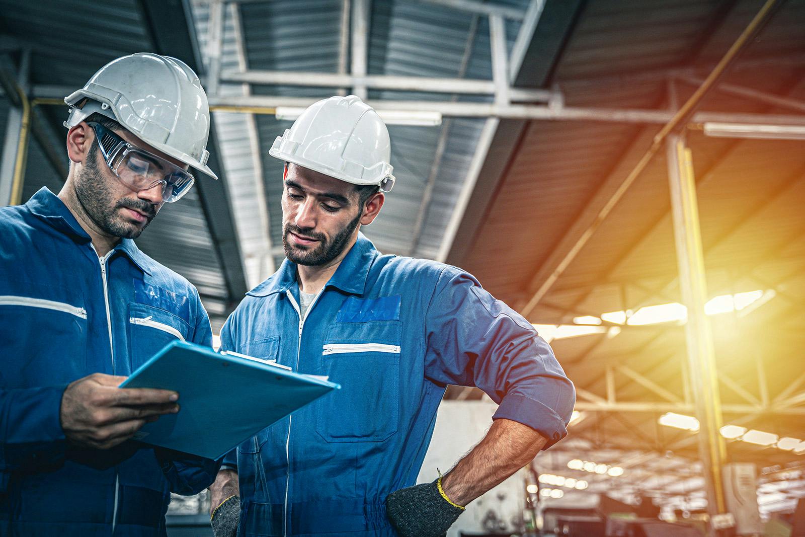 Two workers review an instruction manual together.